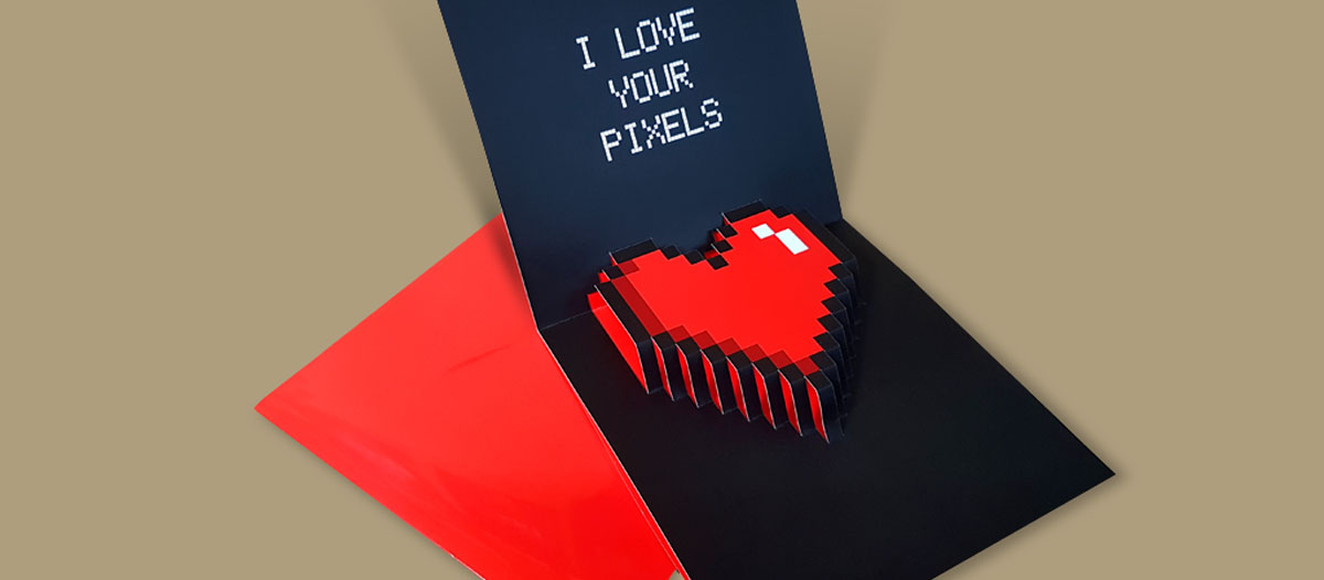 Tarjeta pop up para felicitar el Día de San Valentín. Con un diseño de un corazón troquelado, como si estuviera hecho con pixeles que se despliega cuando se abre la tarjeta